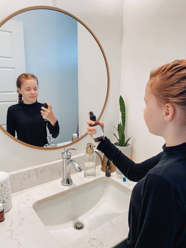 teen spraying toner on face