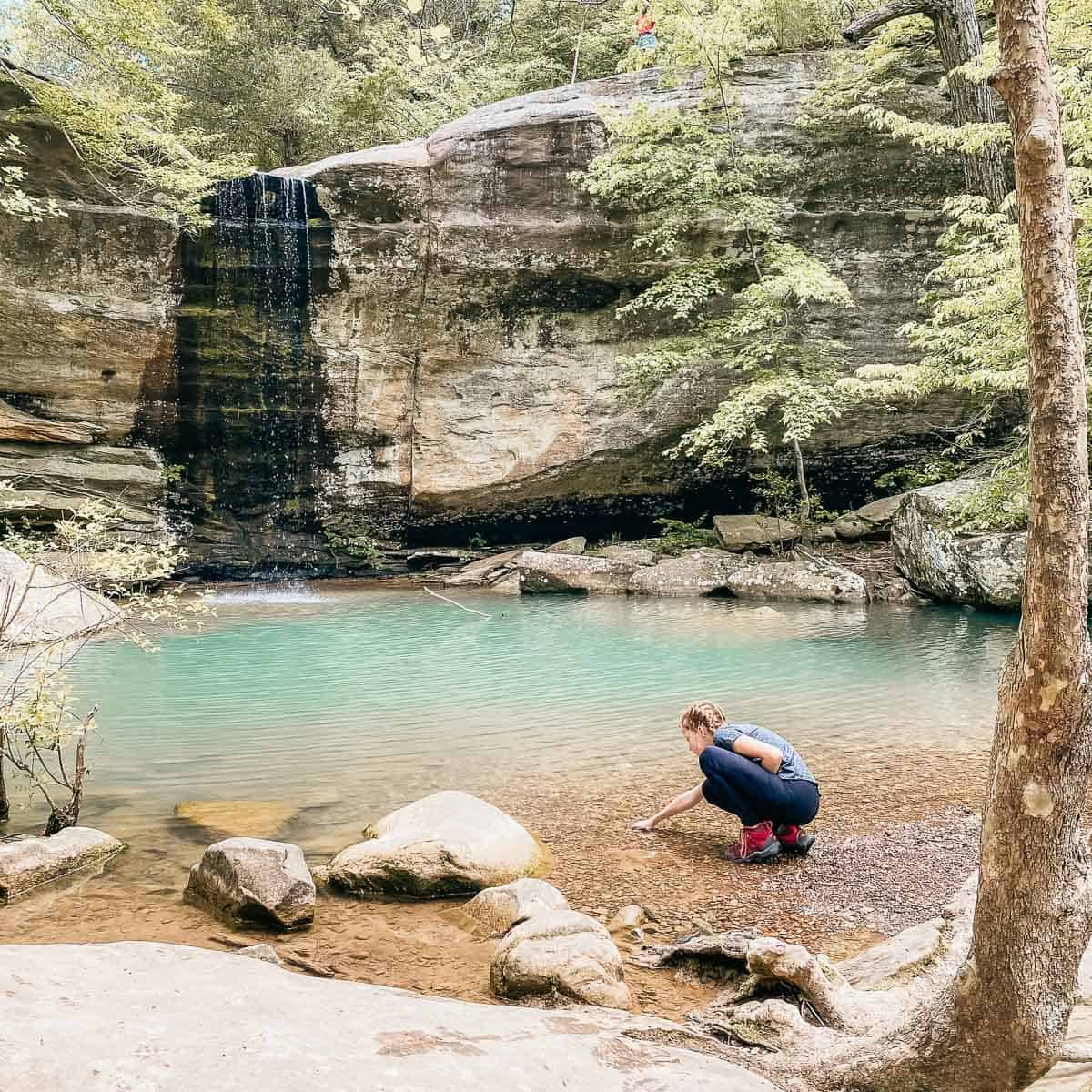 girl feeling water from a waterfall