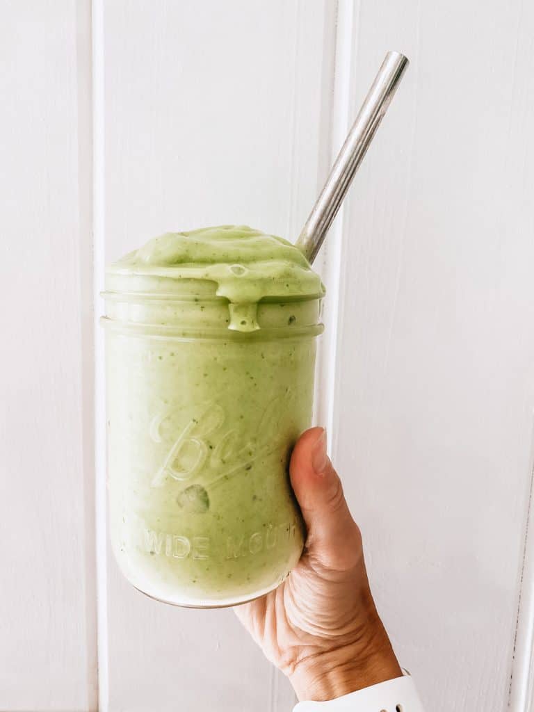 green smoothie held in front of shiplap wall