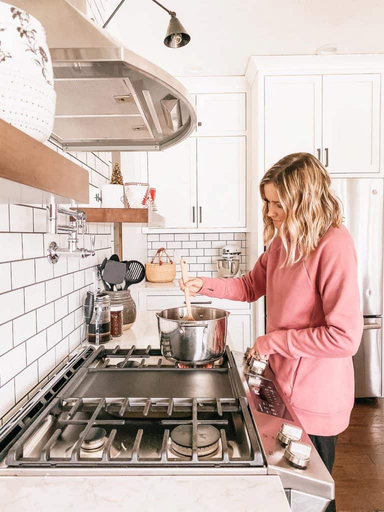 Woman cooking tomato soup over a stove